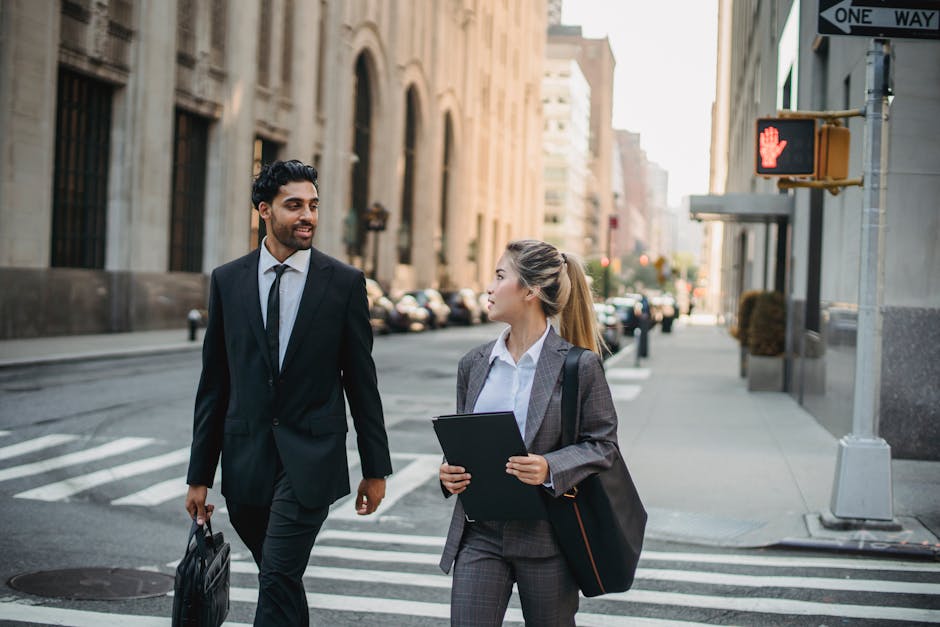 Two professionals in business attire discussing on a city street, exuding confidence and collaboration